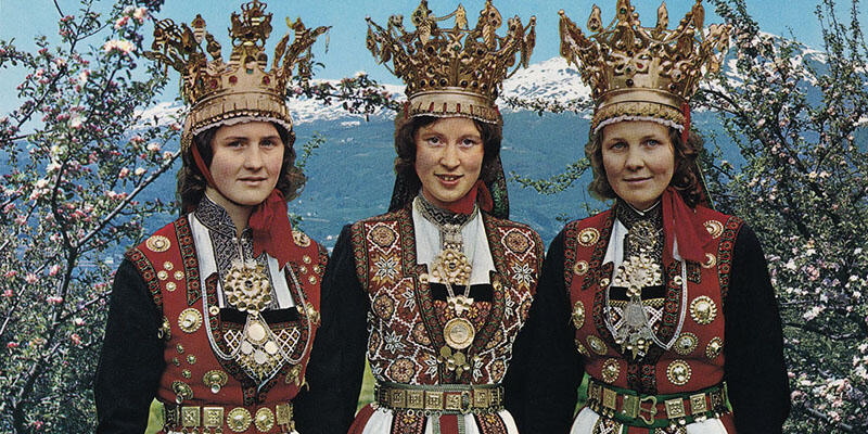Tre kvinnor i ett fjällandskap klädda i norsk folkdräkt